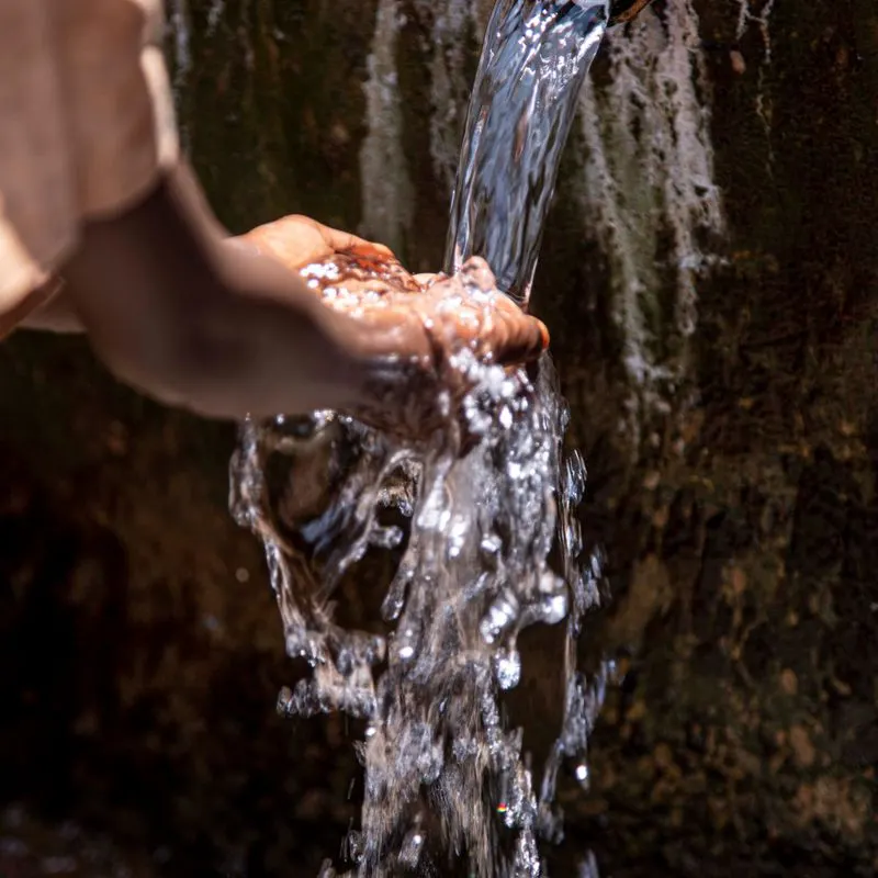 Manos recibiendo agua limpia de un manantial