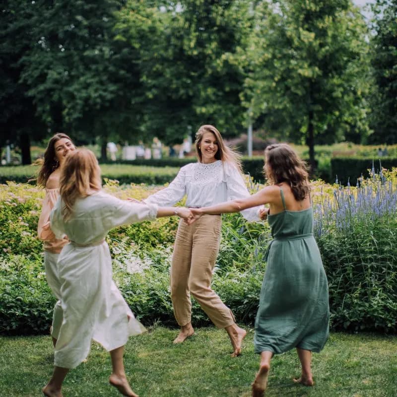 Mujeres bailando juntas tomadas de las manos en un parque